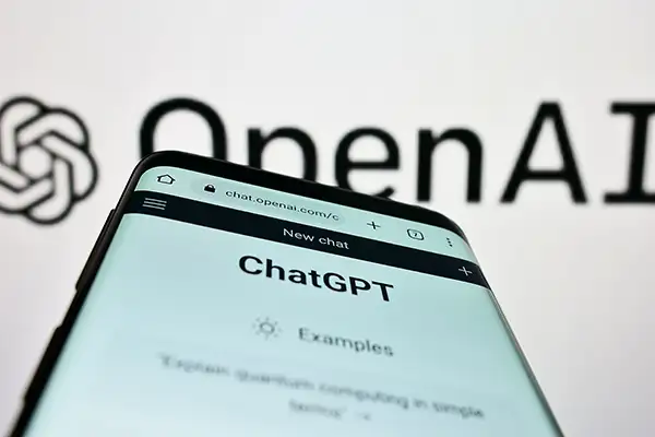 ChatGPT on a phone in front of OpenAI logo in background ChatGPT on a phone in front of OpenAI logo in background